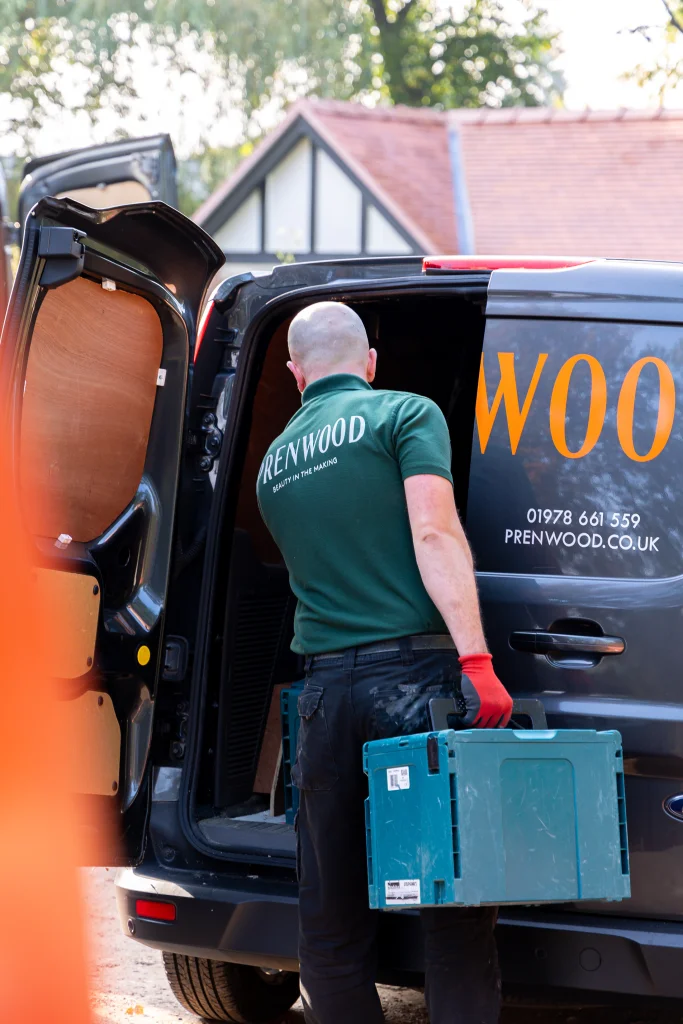 Prenwood worker unloading a toolbox from a van with company branding.