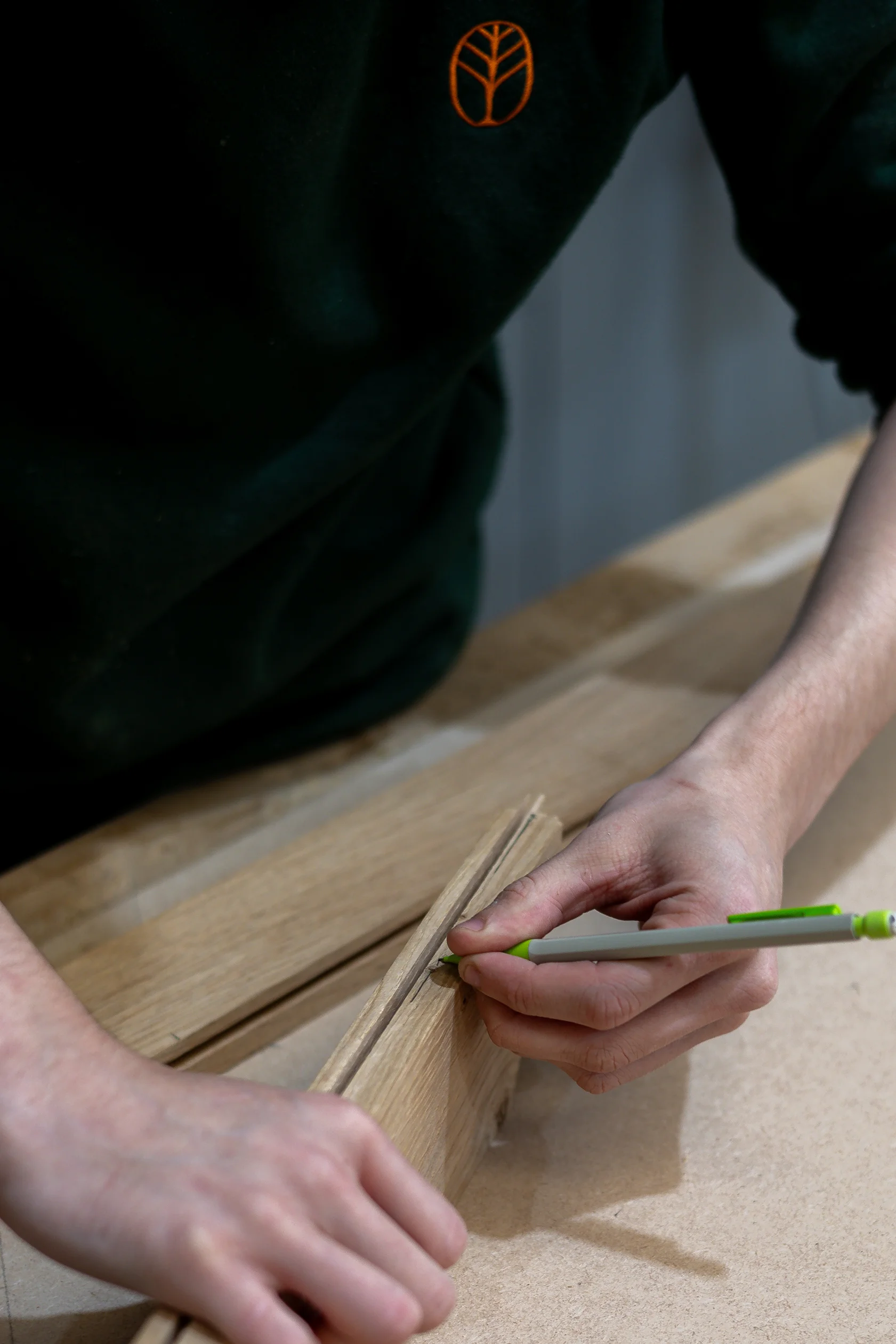 A person is measuring and marking pieces of wood.