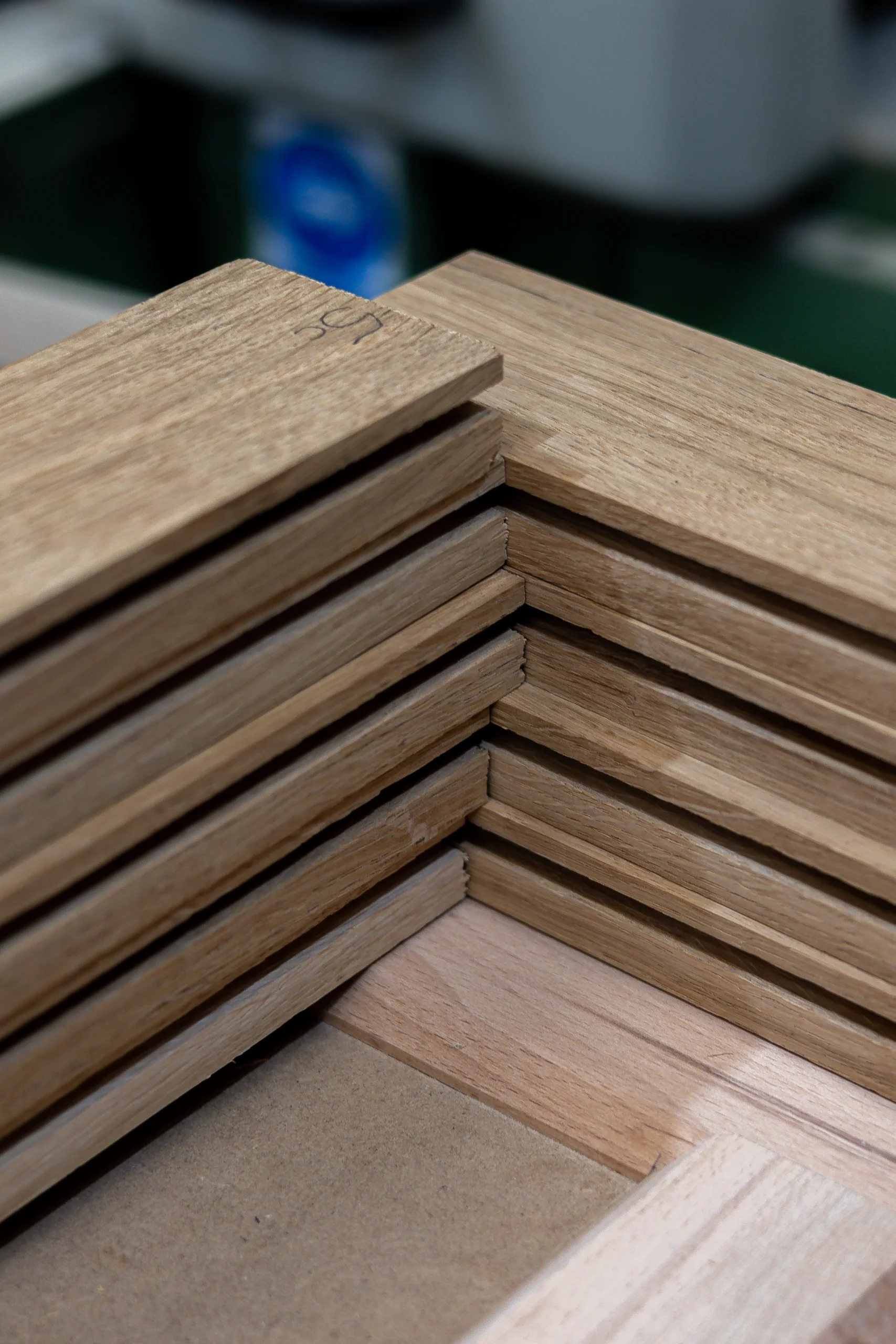 Stacked unfinished wooden flooring planks arranged in a neat corner showing tongue-and-groove edges and wood grain.