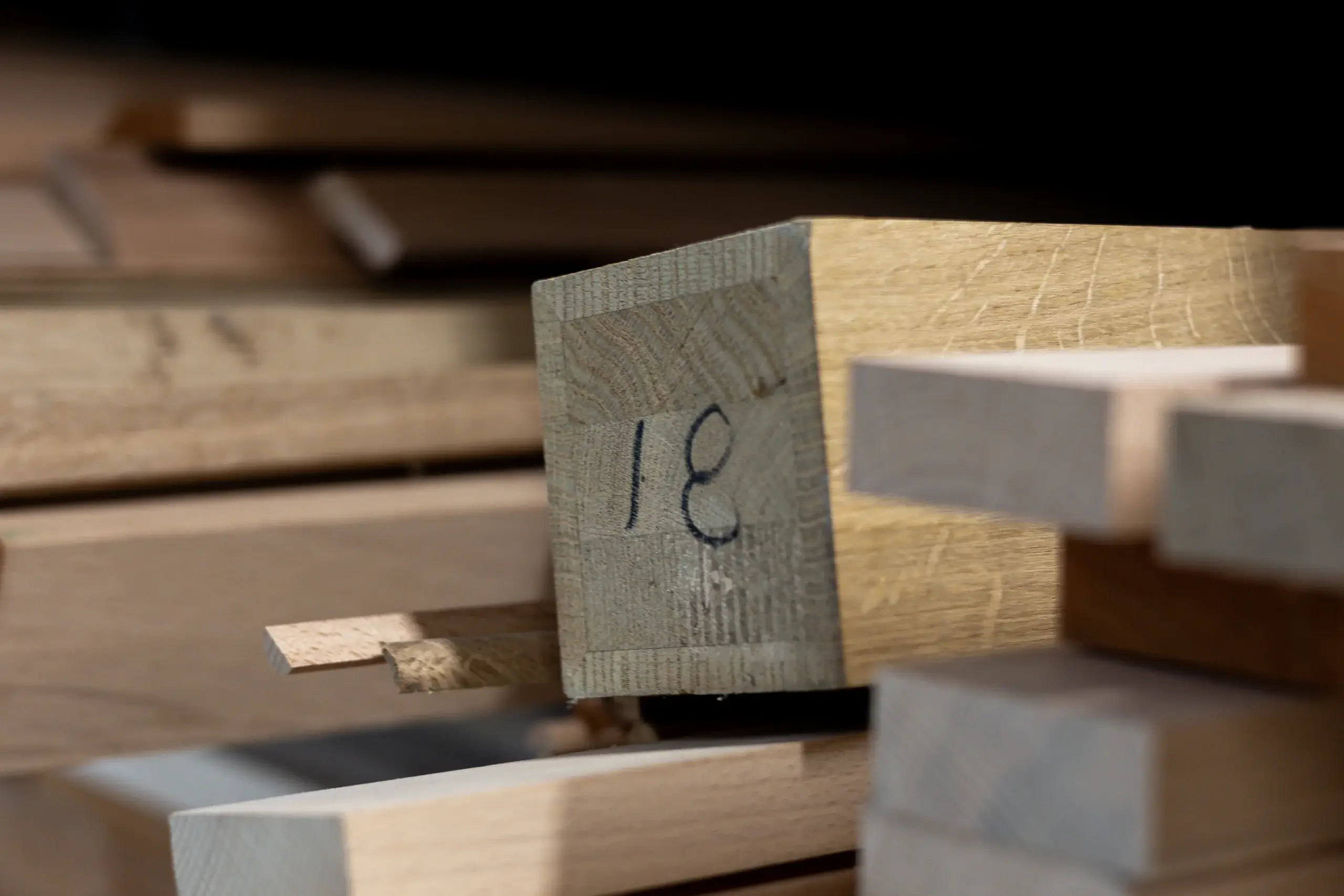 Stacked wooden boards with a squared end piece marked "18" in black marker, surrounded by other cut lumber pieces.