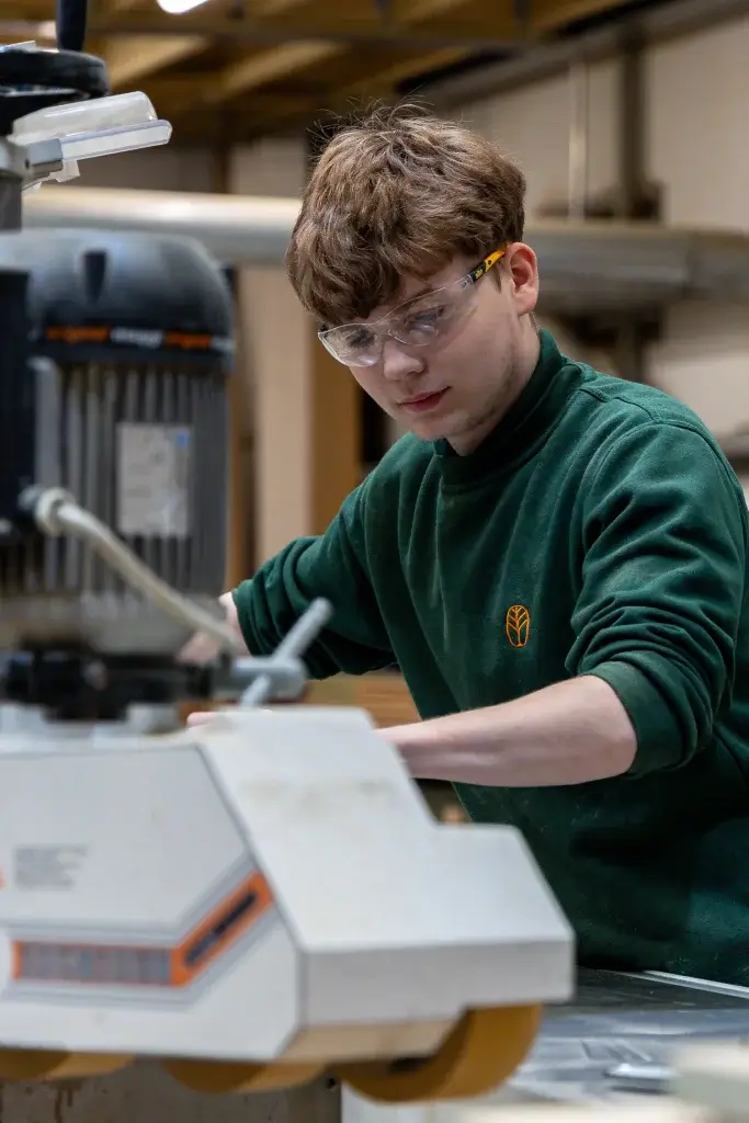 A young man working on a machine in a factory with Prenwood uniform