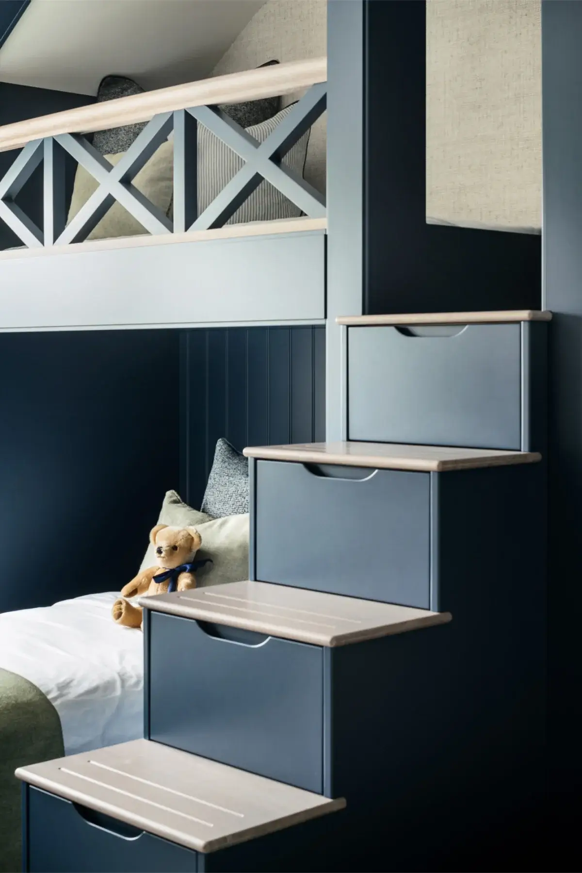 A finished built in bunk bed with steps and drawers in blue.