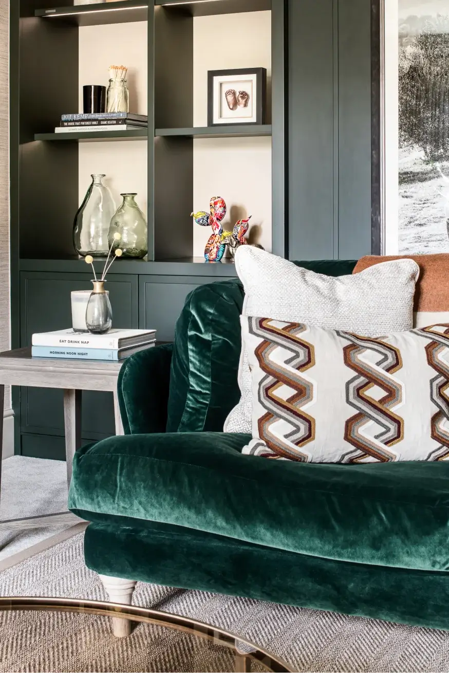 green sofa with side table in front of a fitted storage wall