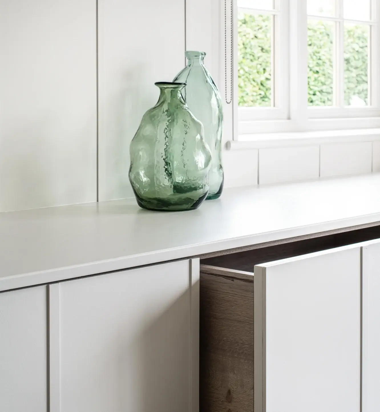 Open drawer of a storage bench with a glass vase on the top