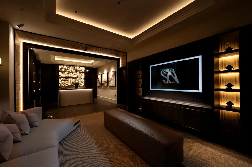 Dim lit lounge with large cream sofa and full length media wall