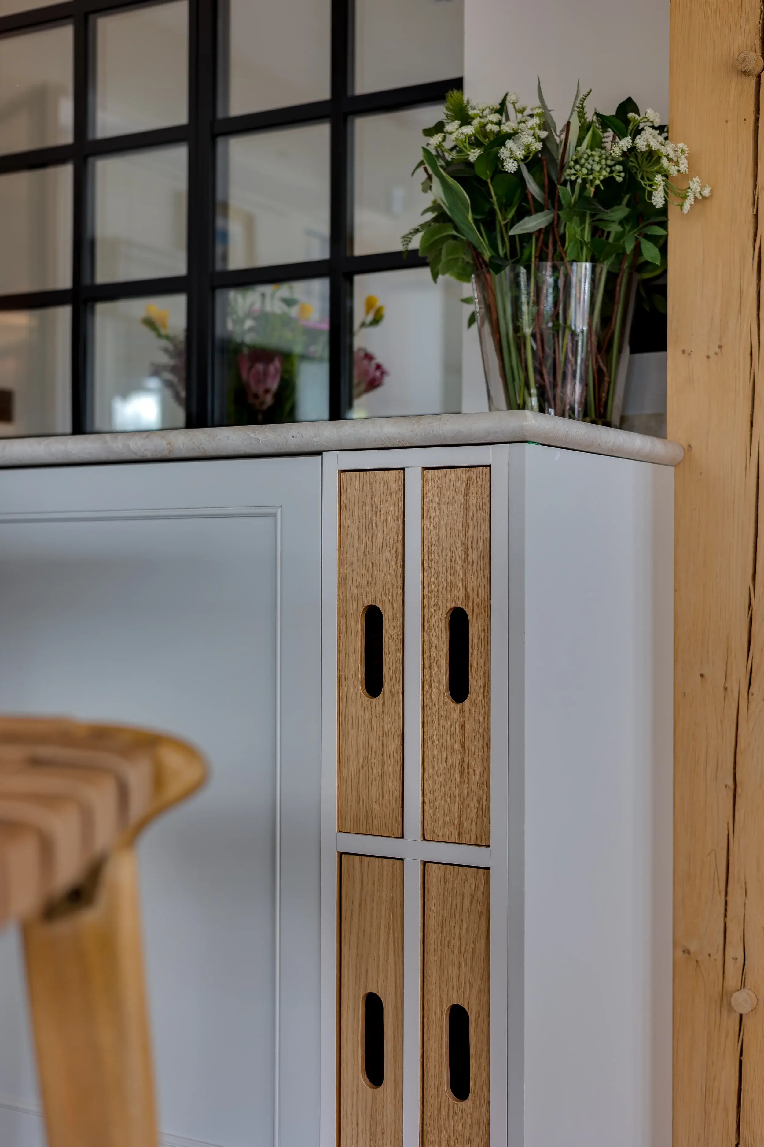 Close-up of bespoke kitchen cabinetry featuring inset oak pull-out storage slots and quartz worktop.