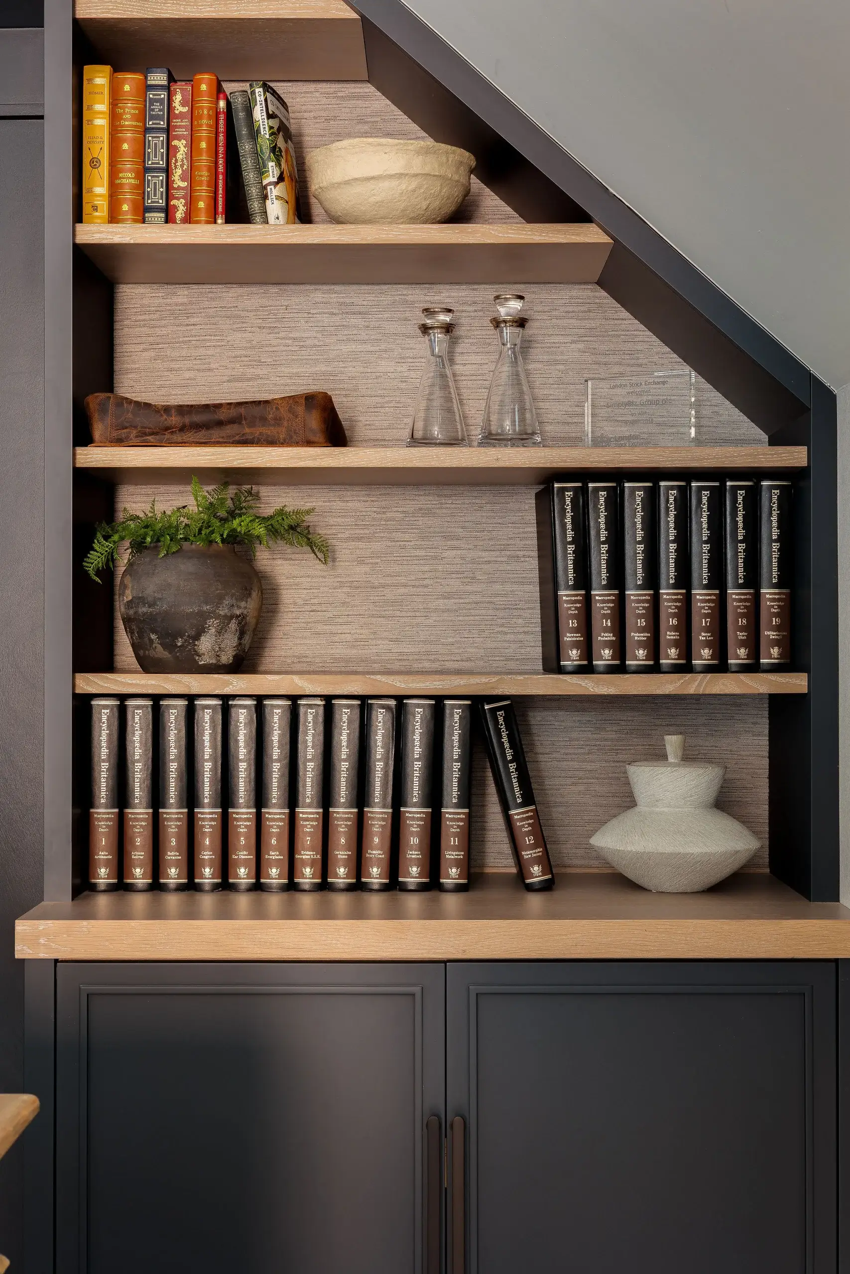 Built-in bookcase with angled shelving, oak accents, and integrated storage, showcasing bespoke joinery craftsmanship.
