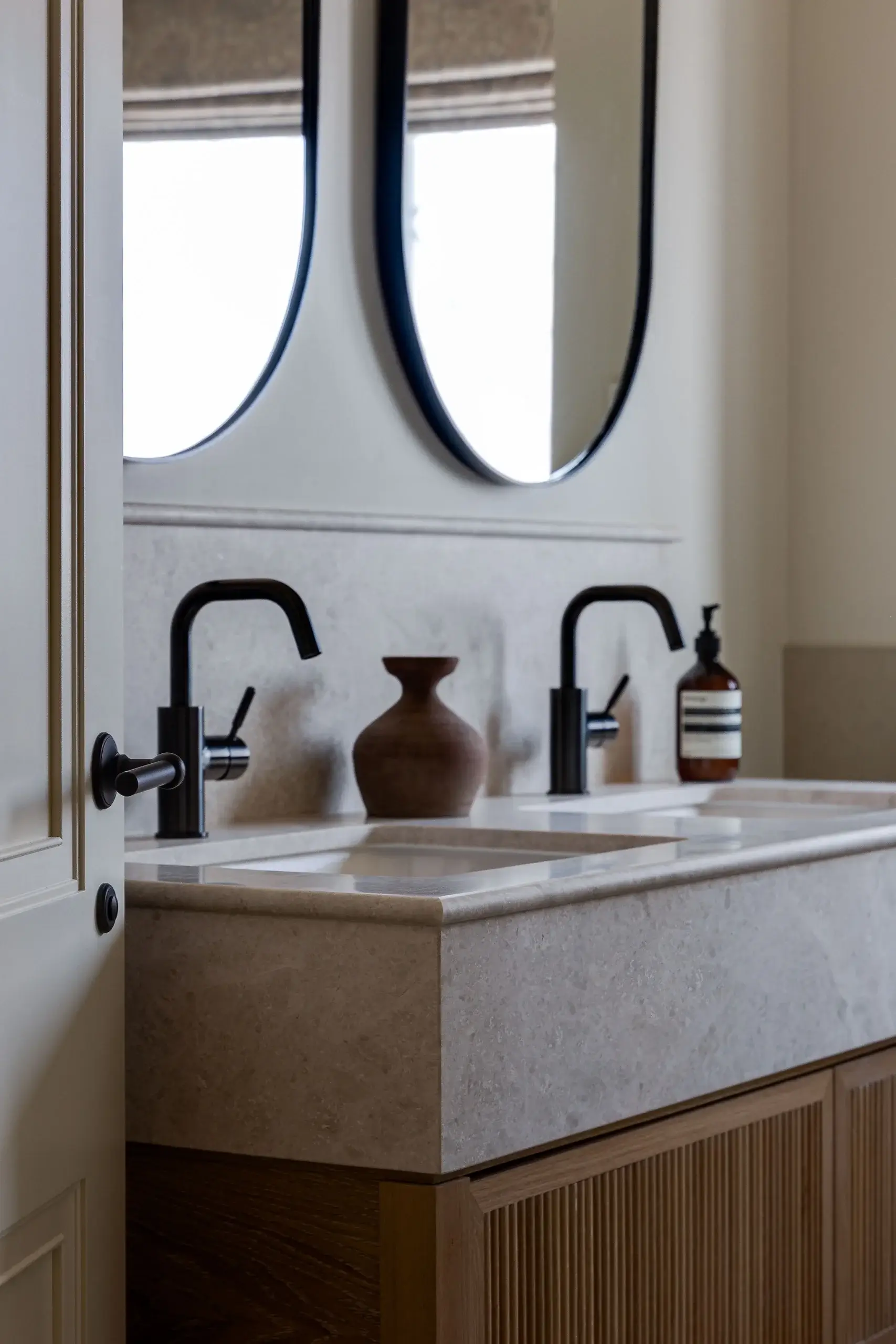 Fluted oak vanity with soft stone worktop, featuring dual basins and matte black fixtures.