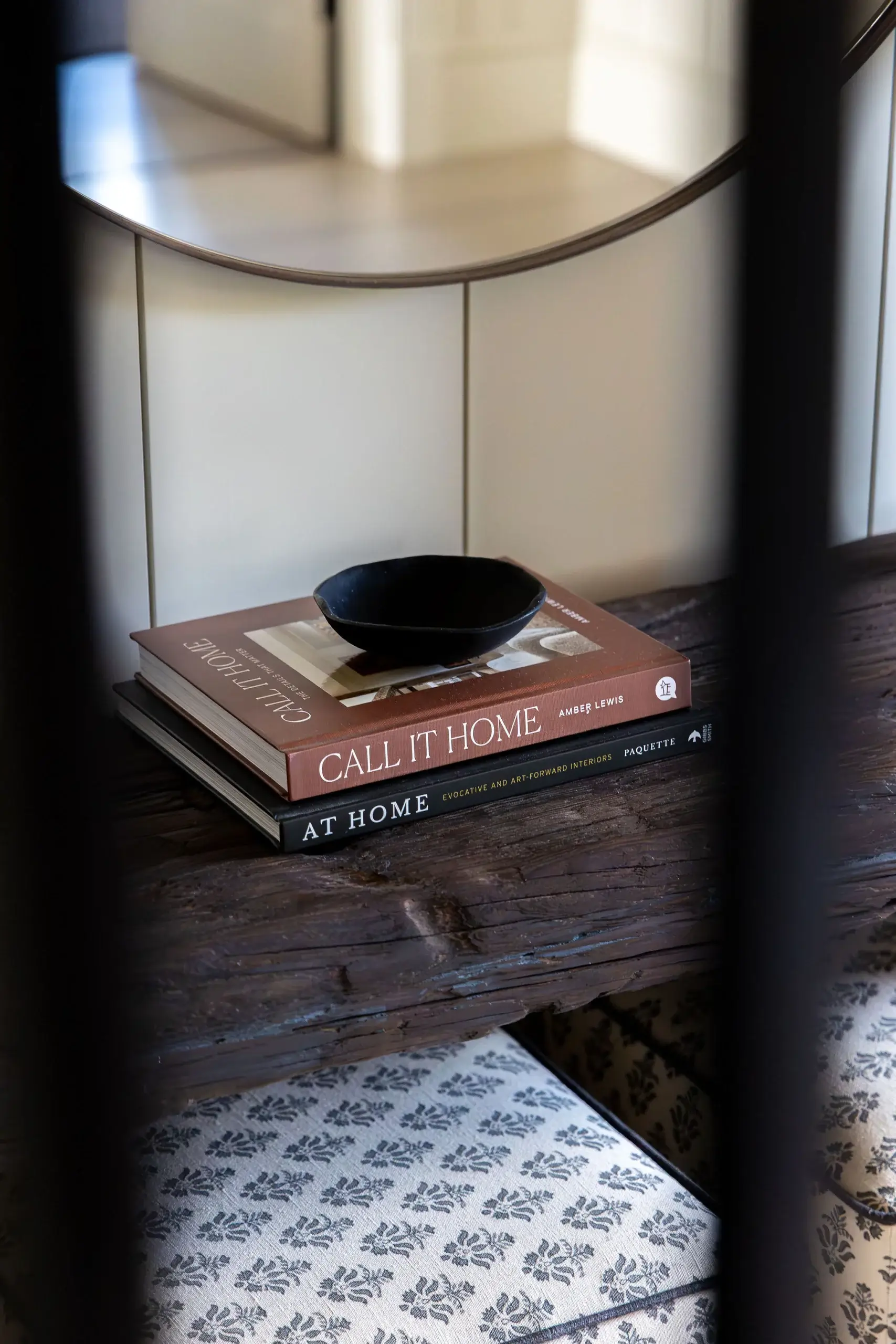Entrance hallway with bespoke timber console table, round mirror, and linen-covered stools beneath.