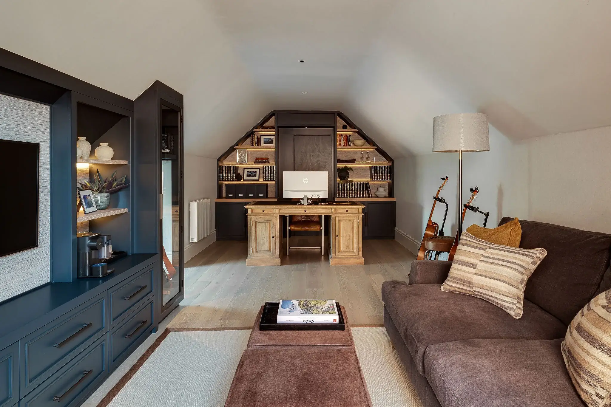 Attic home office with fully fitted joinery, combining oak and painted cabinetry with integrated shelving and desk.