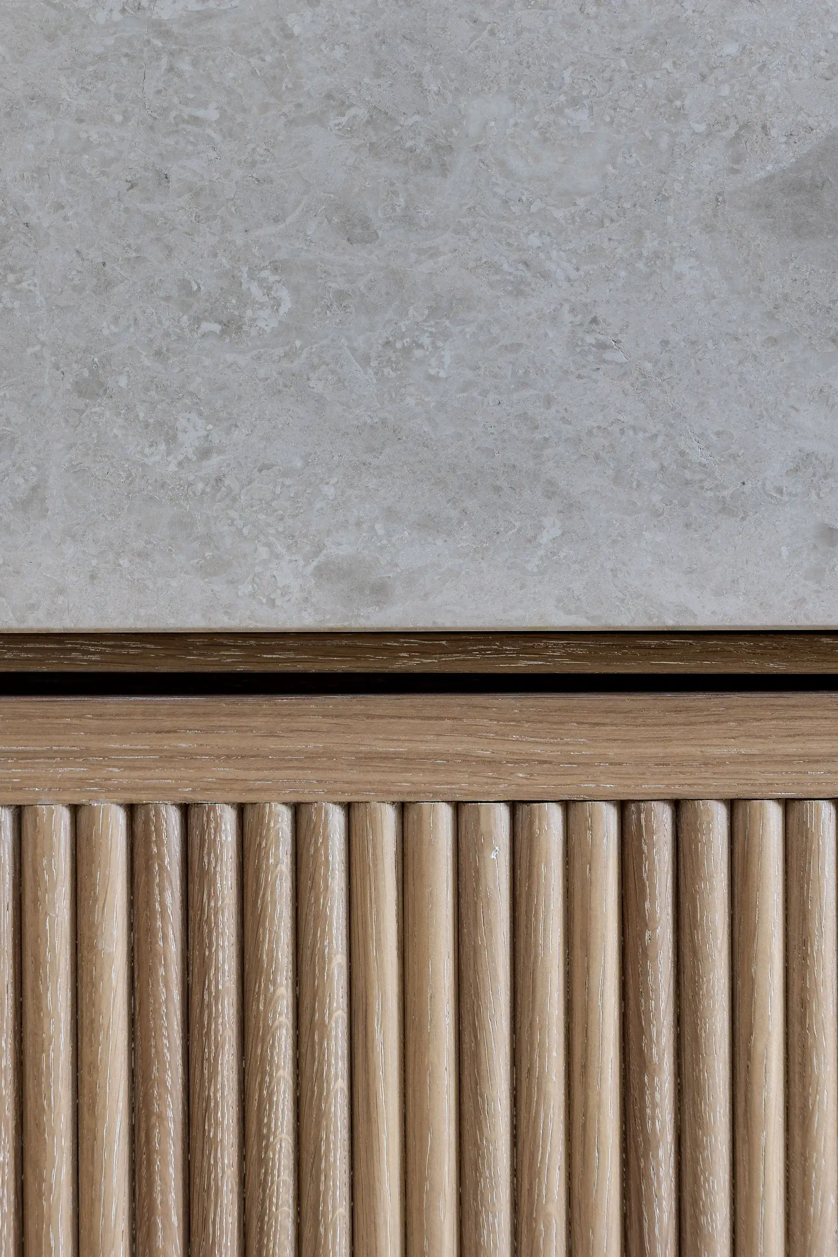 Detail of fluted oak joinery beneath a smooth stone countertop