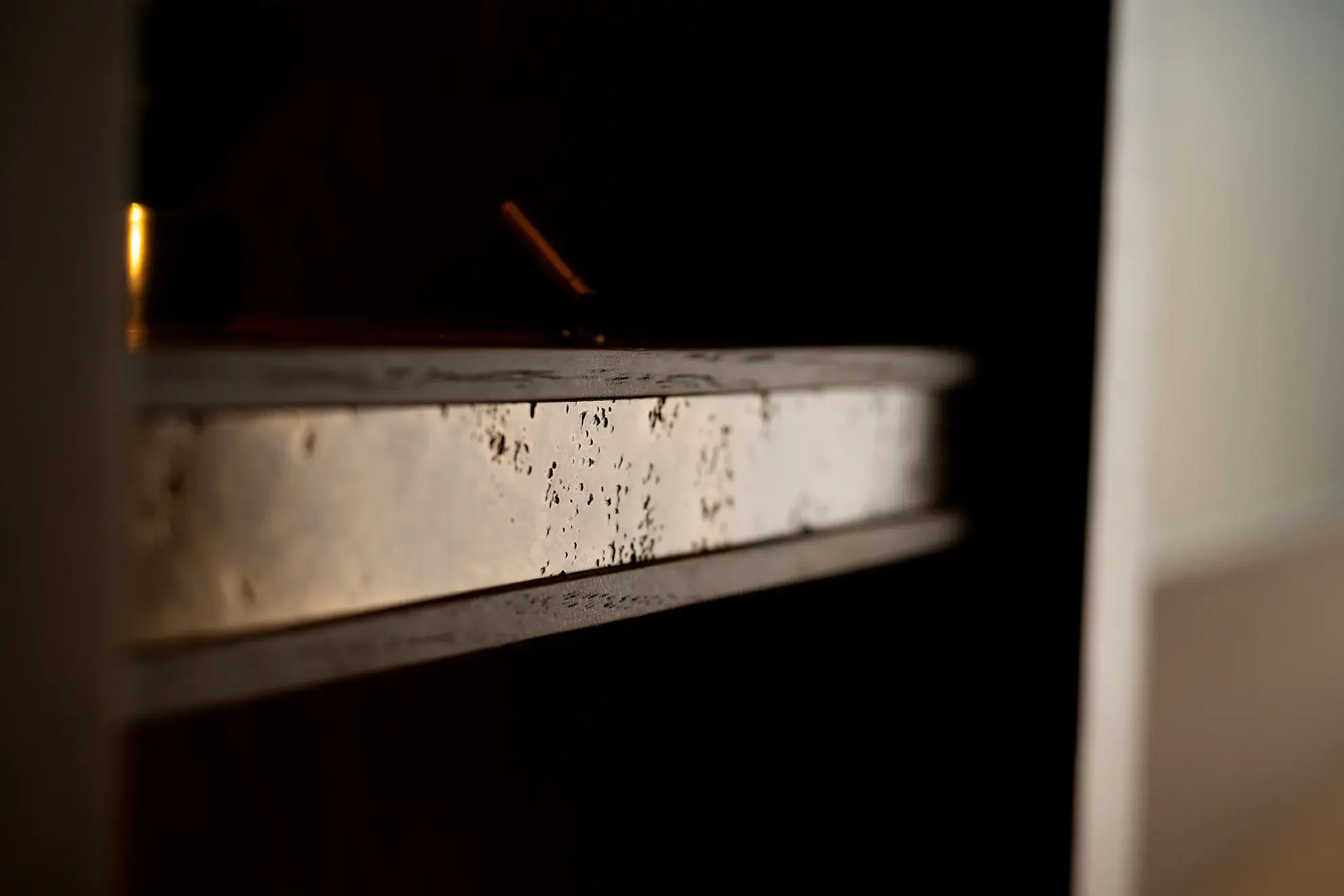 Close-up of bronze or aged metal detail in bespoke shelving unit