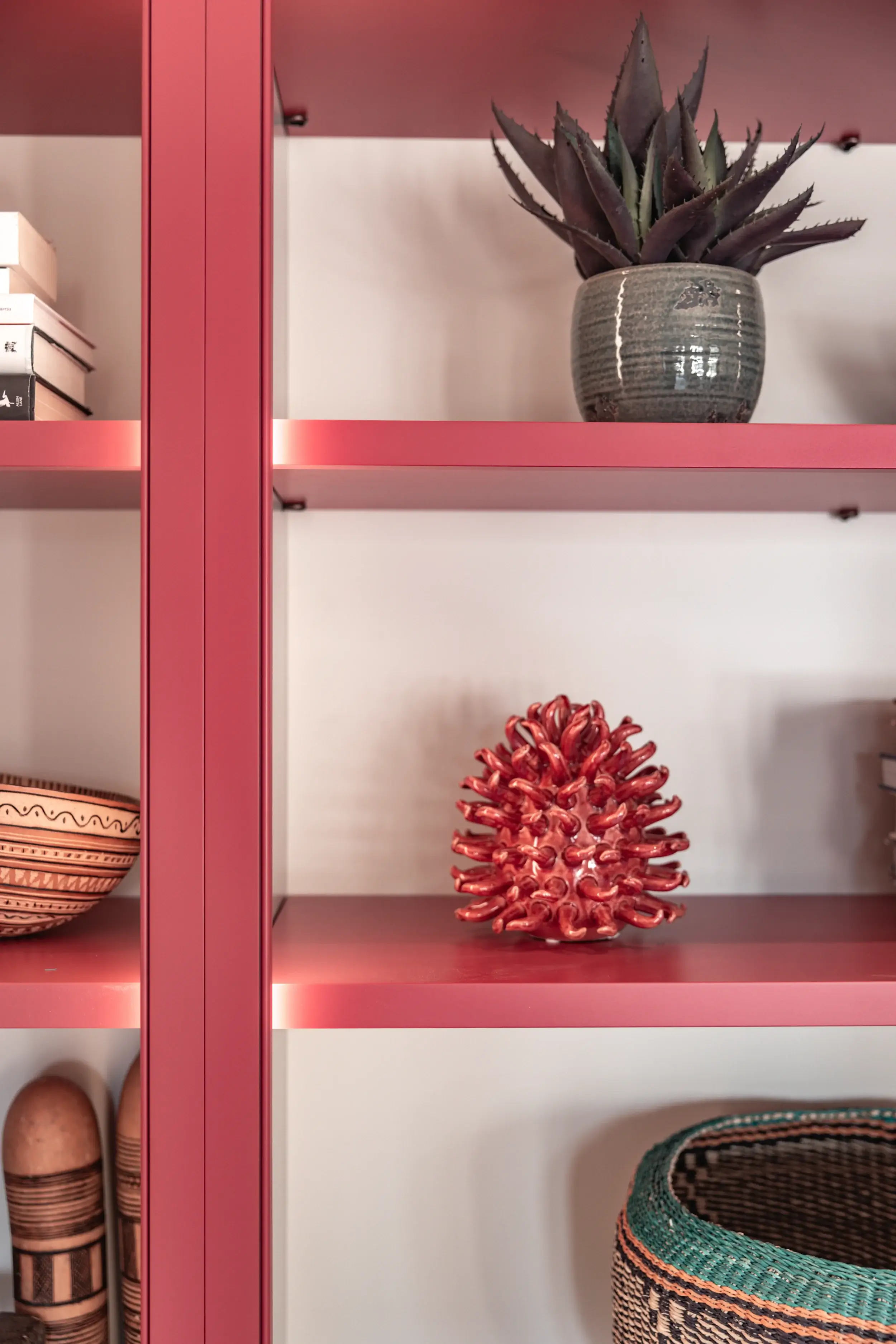 Pink-painted open shelving with display objects and plant styling in bespoke joinery
